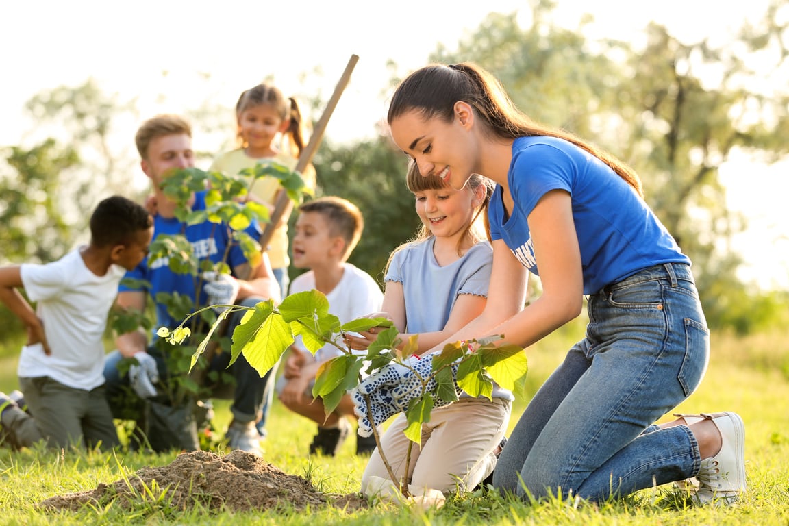 Kids Planting Trees with Volunteers in Park